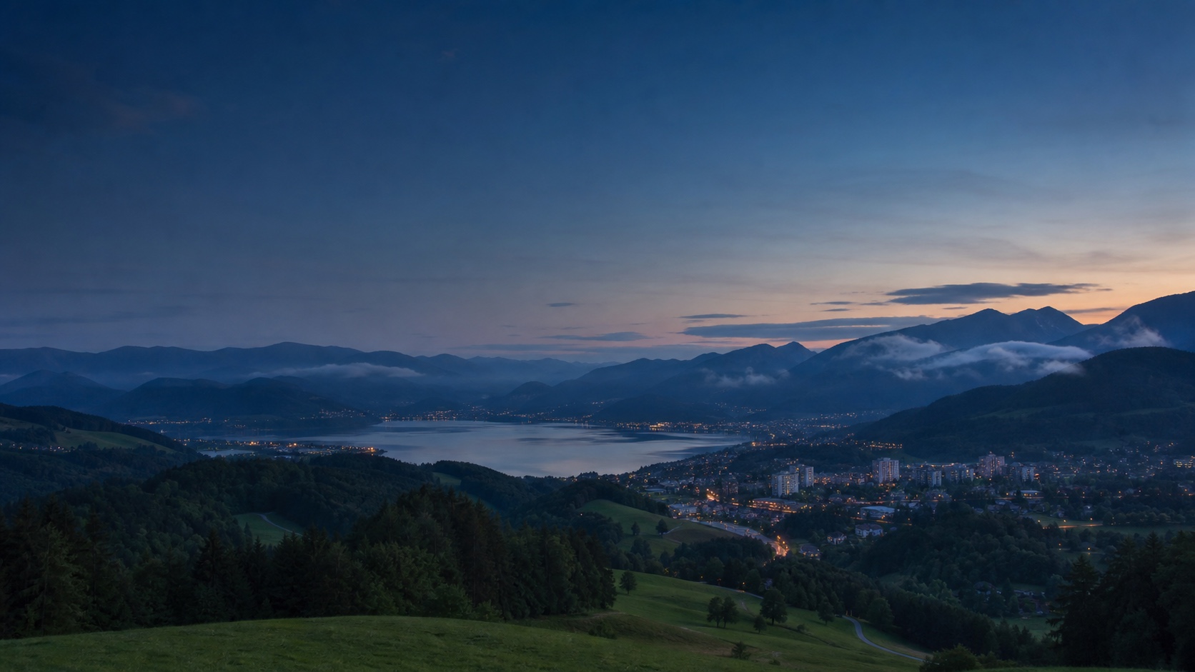 Stylised Southern Austrian perspective with Alpine foothills, a lake, an urban area and connecting roads at blue hour